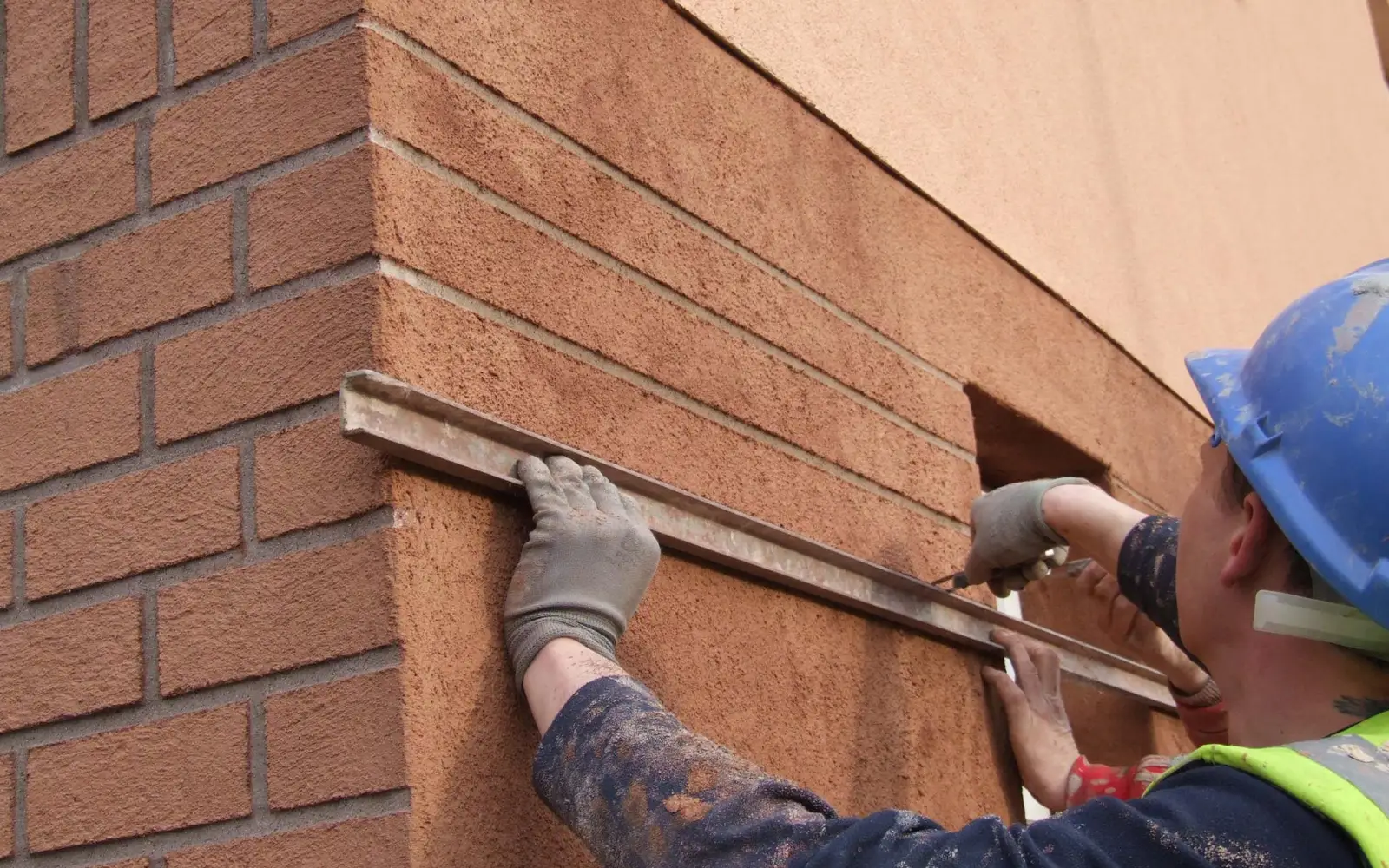 Artisan appliquant un crépi projeté sur une façade à Tarbes